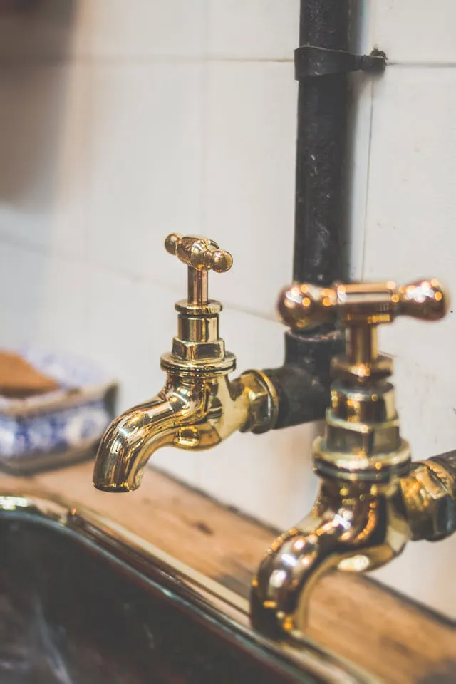 Brass faucets mounted on a pipe above a sink